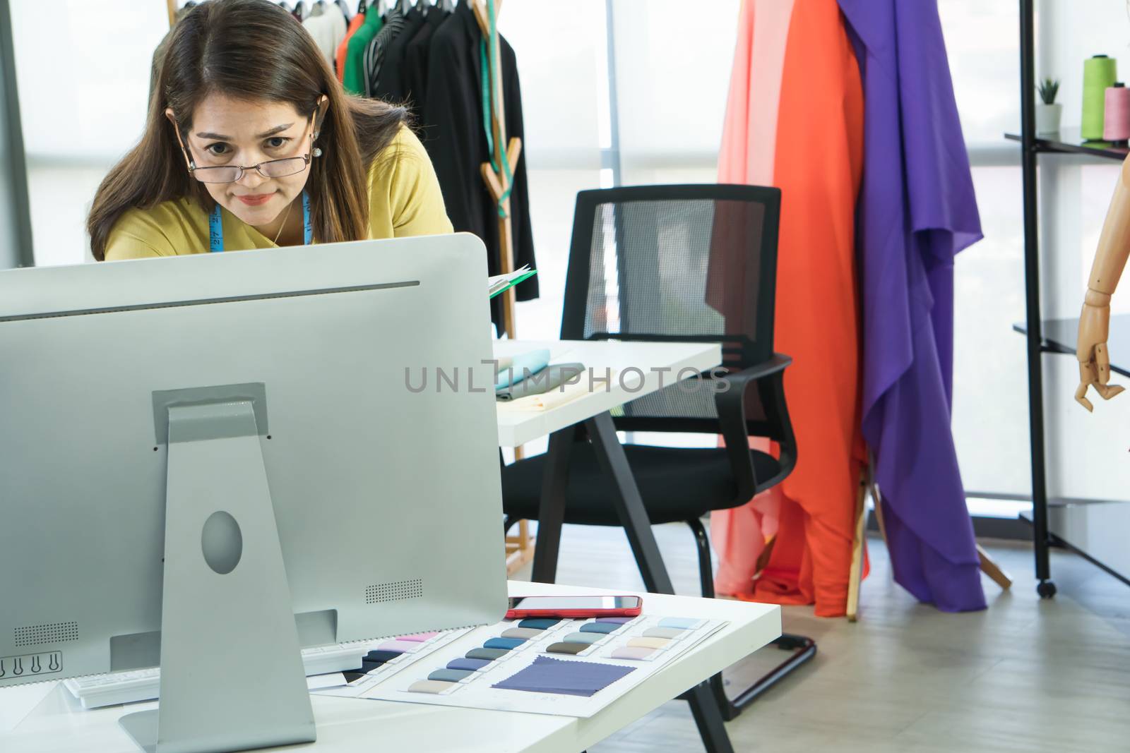 A senior female fashion designer from Asia is working in a textile factory. Confidently with starting a new business And smile at the camera friendly