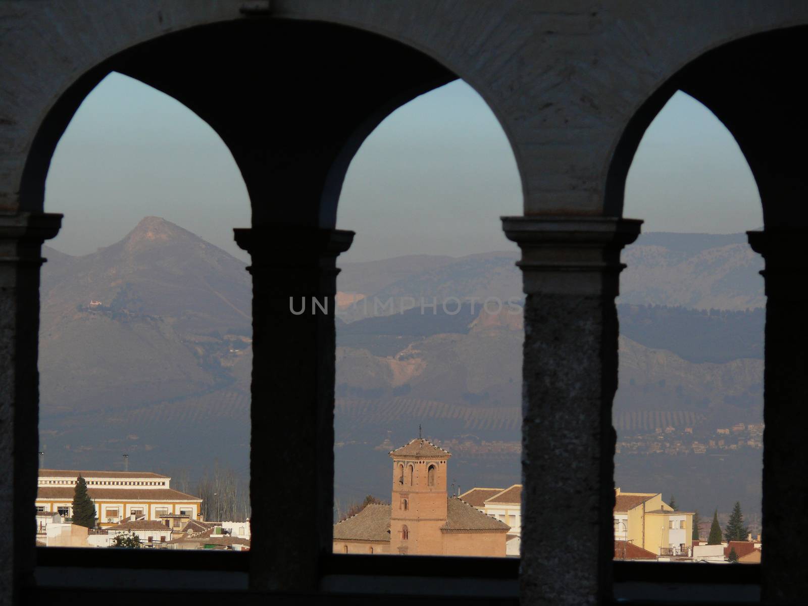 The city of Granada framed by the arches of a portico. by Paolo_Grassi