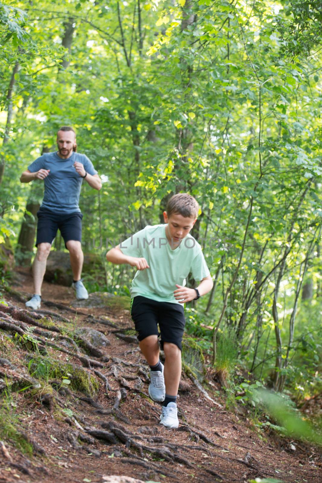 Father and son run in forest together, care, sport, parenting, healthy lifestyle concept