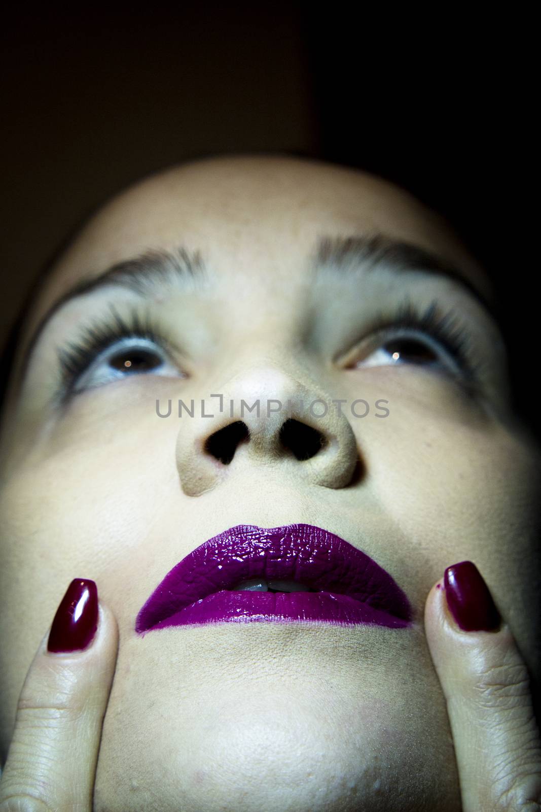 Portrait of woman with hand over face. Red makeup lips and nails