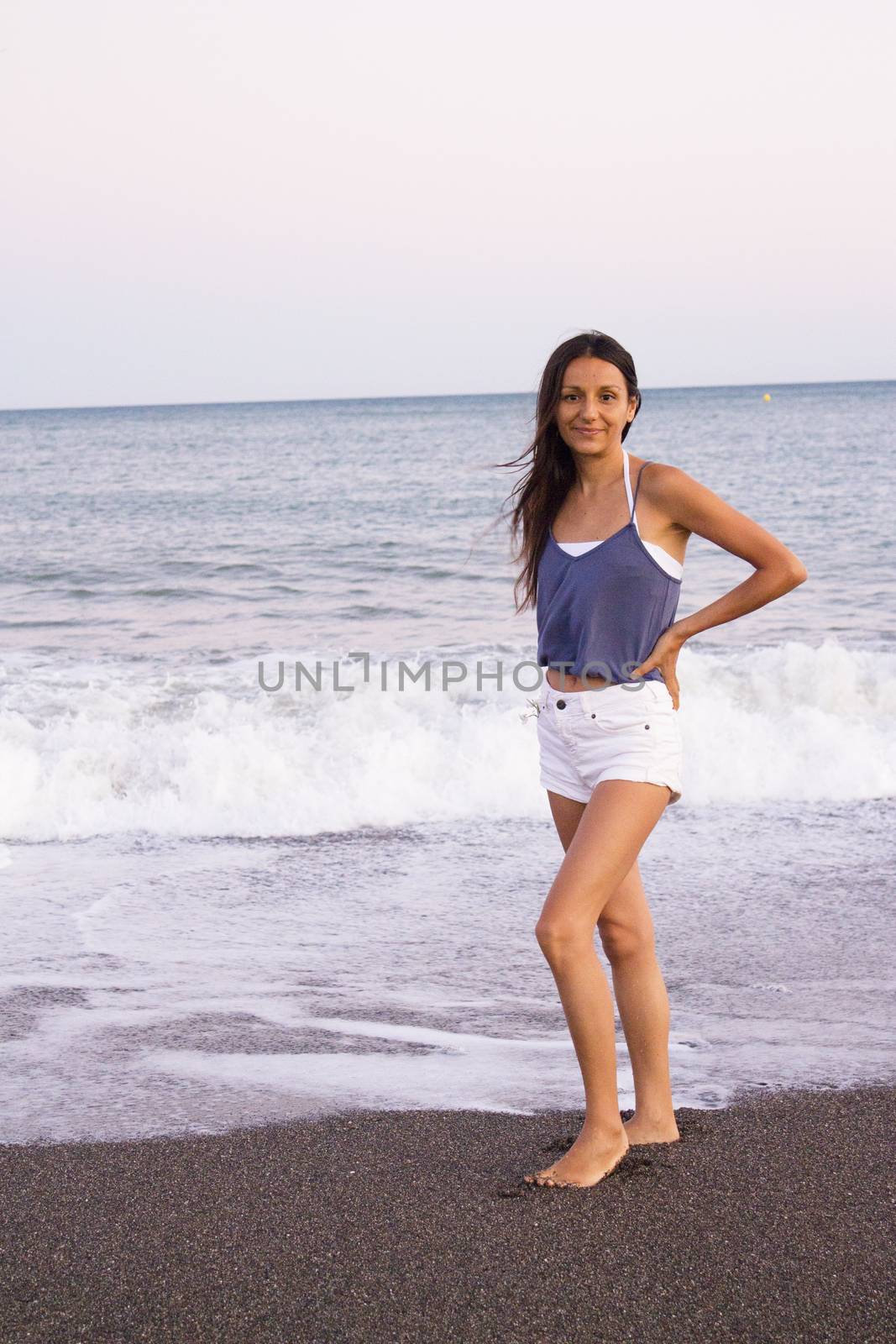 Mujer joven en la playa en actitud muy positiva y feliz. Precioso atardecer