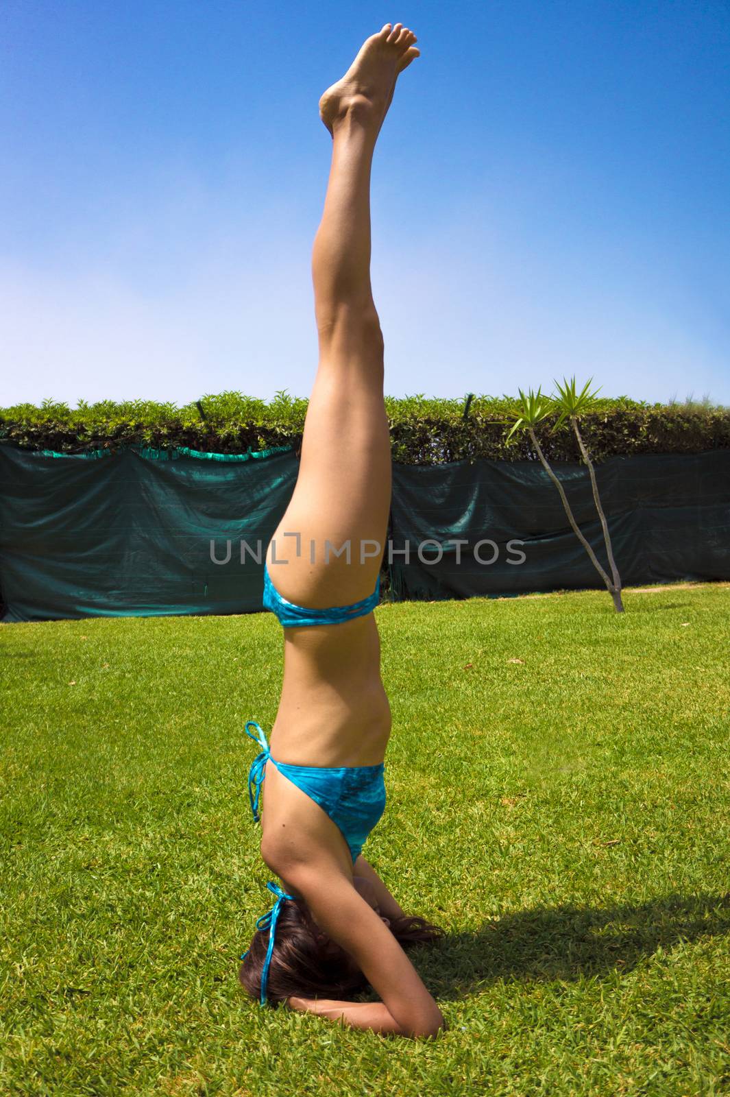 Slim woman in bikini practicing yoga. Sirsasana position