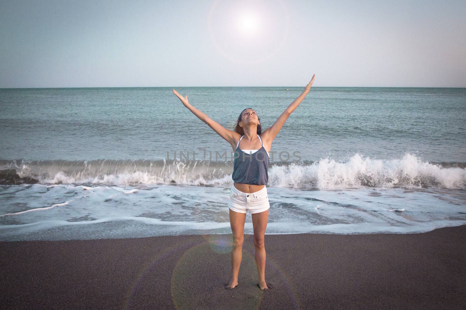 Mujer joven en la playa en actitud muy positiva y feliz. Precioso atardecer