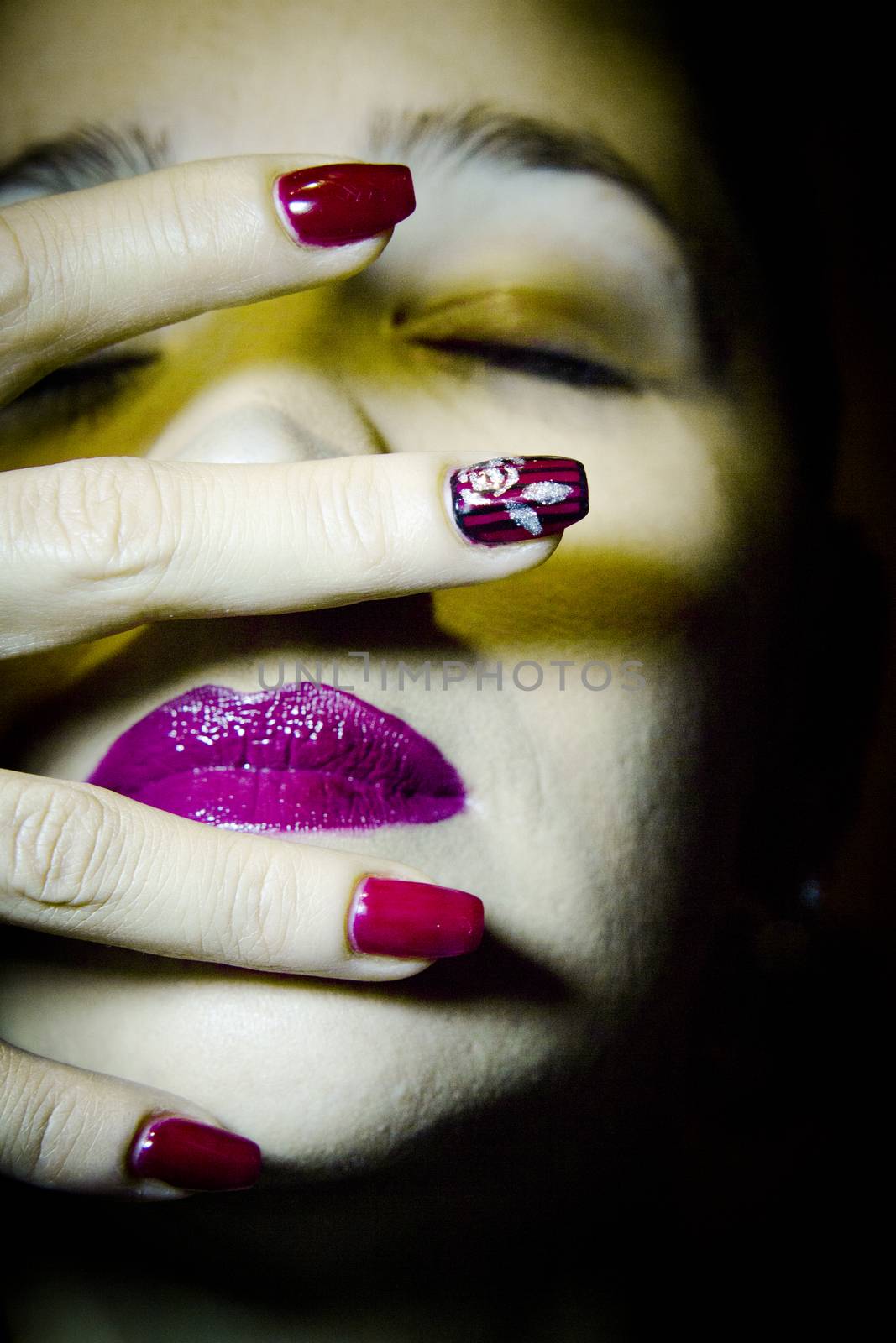 Portrait of woman with hand over face. Red makeup lips and nails
