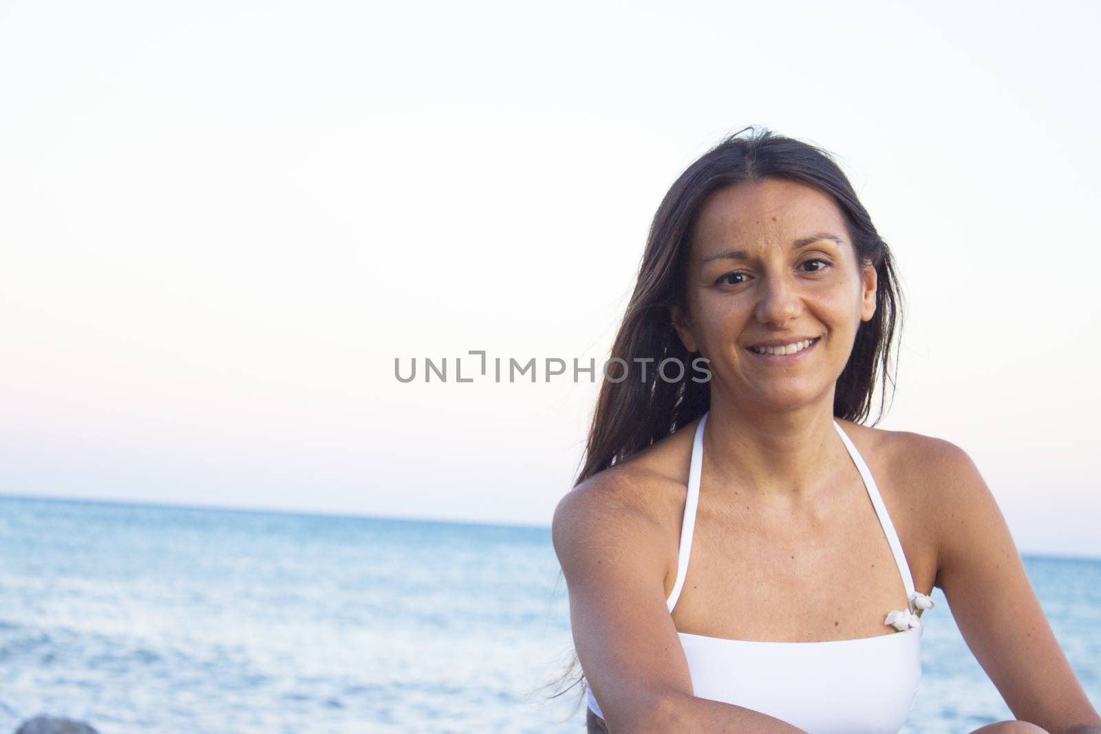 Portrait of young woman with sunset on the beach. Positive, relaxed and calm attitude