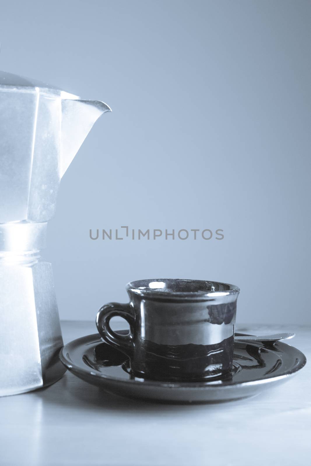 Cup of coffee next to classic Italian coffee maker