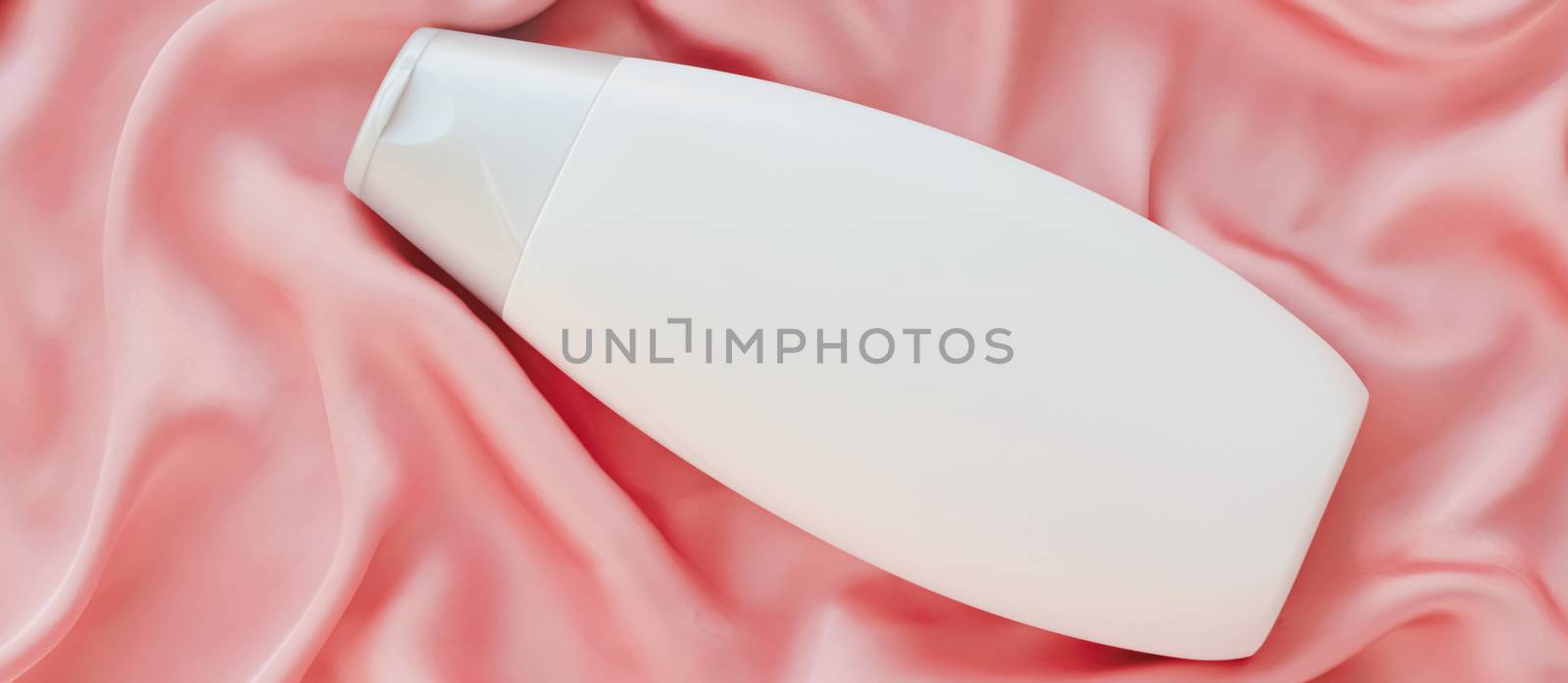 Blank label cosmetic container bottle as product mockup on pink silk background, hygiene and healthcare