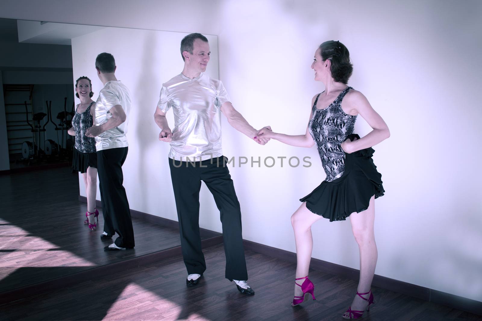Couple of dancers with attractive Latin costumes dancing salsa and different Latin Caribbean rhythms