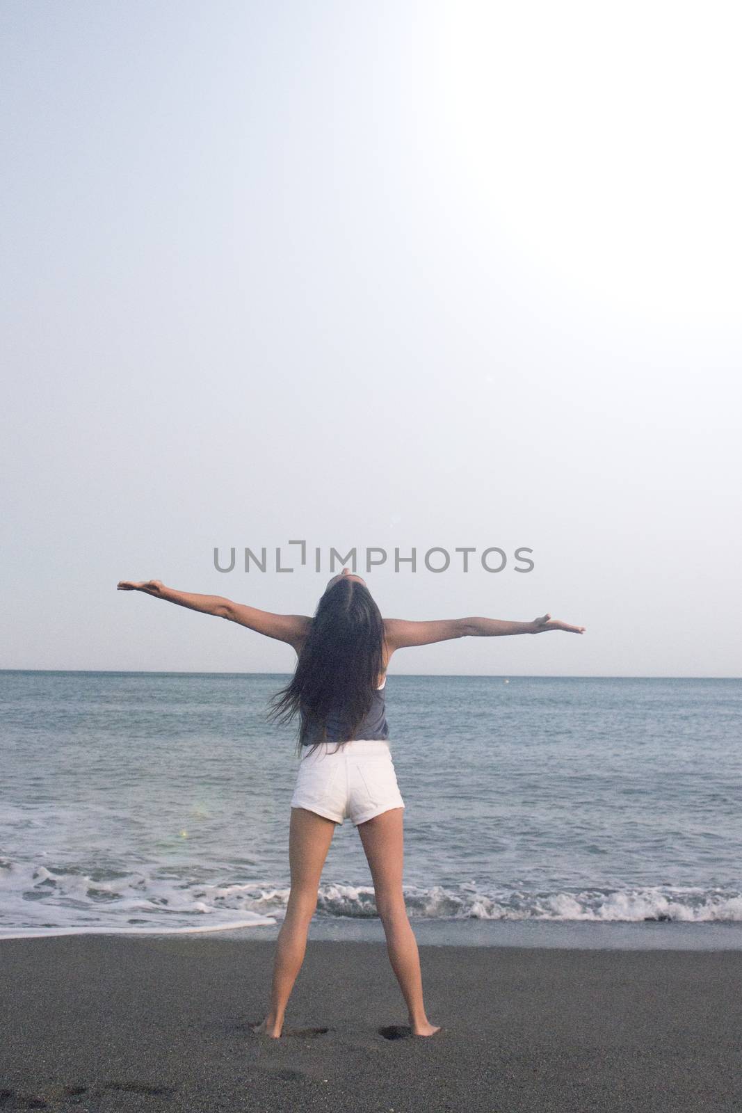 Mujer joven en la playa en actitud muy positiva y feliz. Precioso atardecer