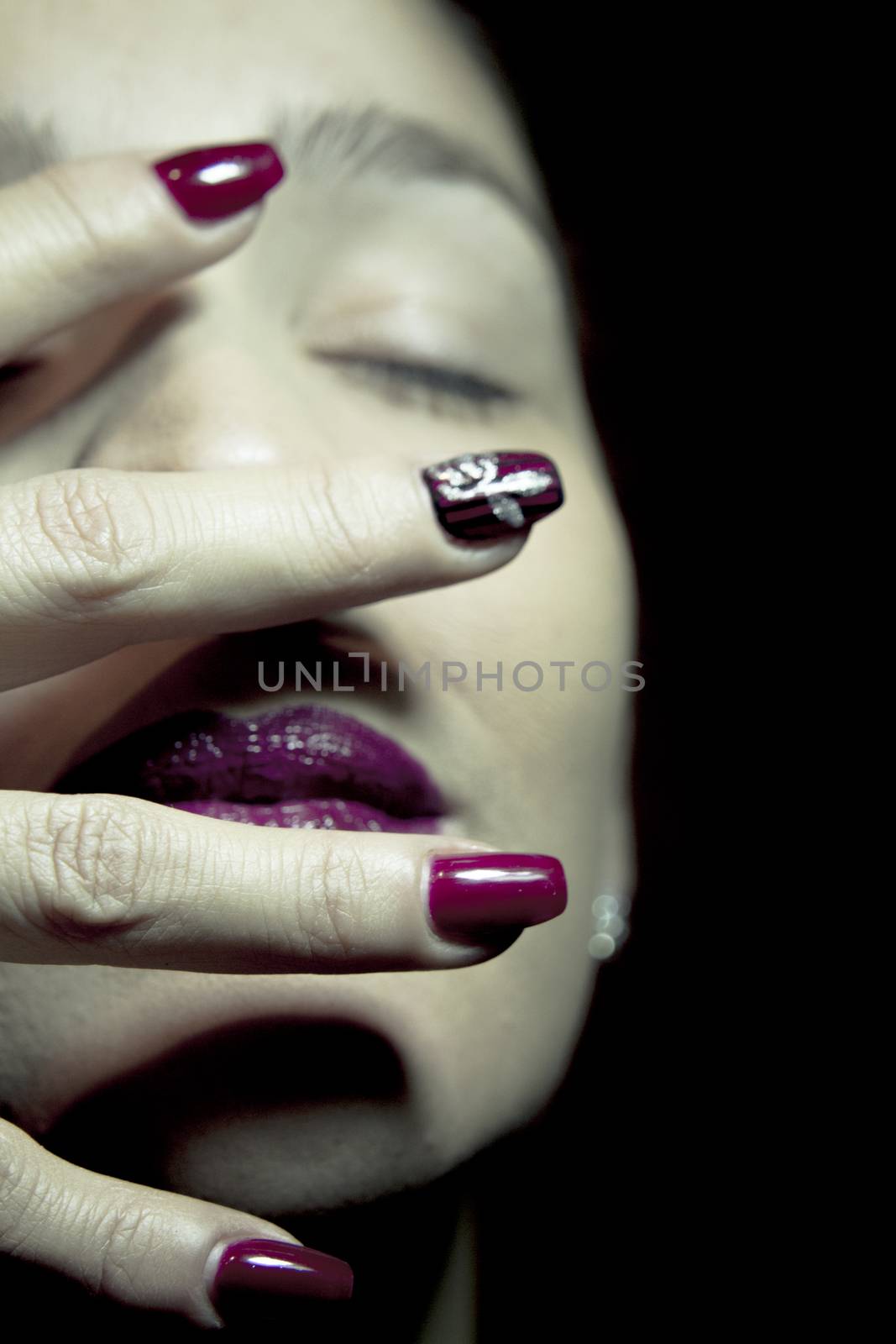 Portrait of woman with hand over face. Red makeup lips and nails