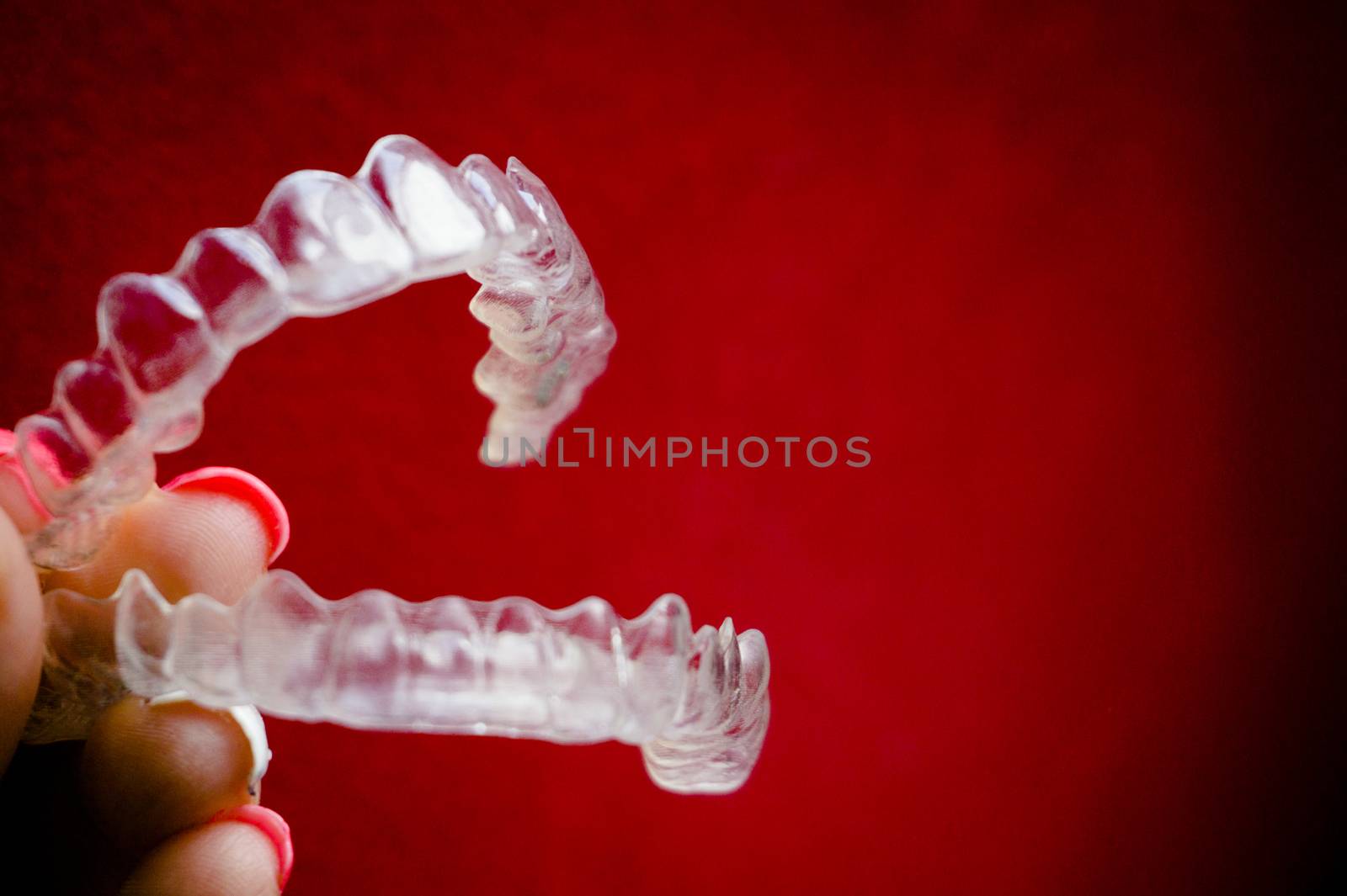 Invisible dental retainer held by womans hand. Copy space