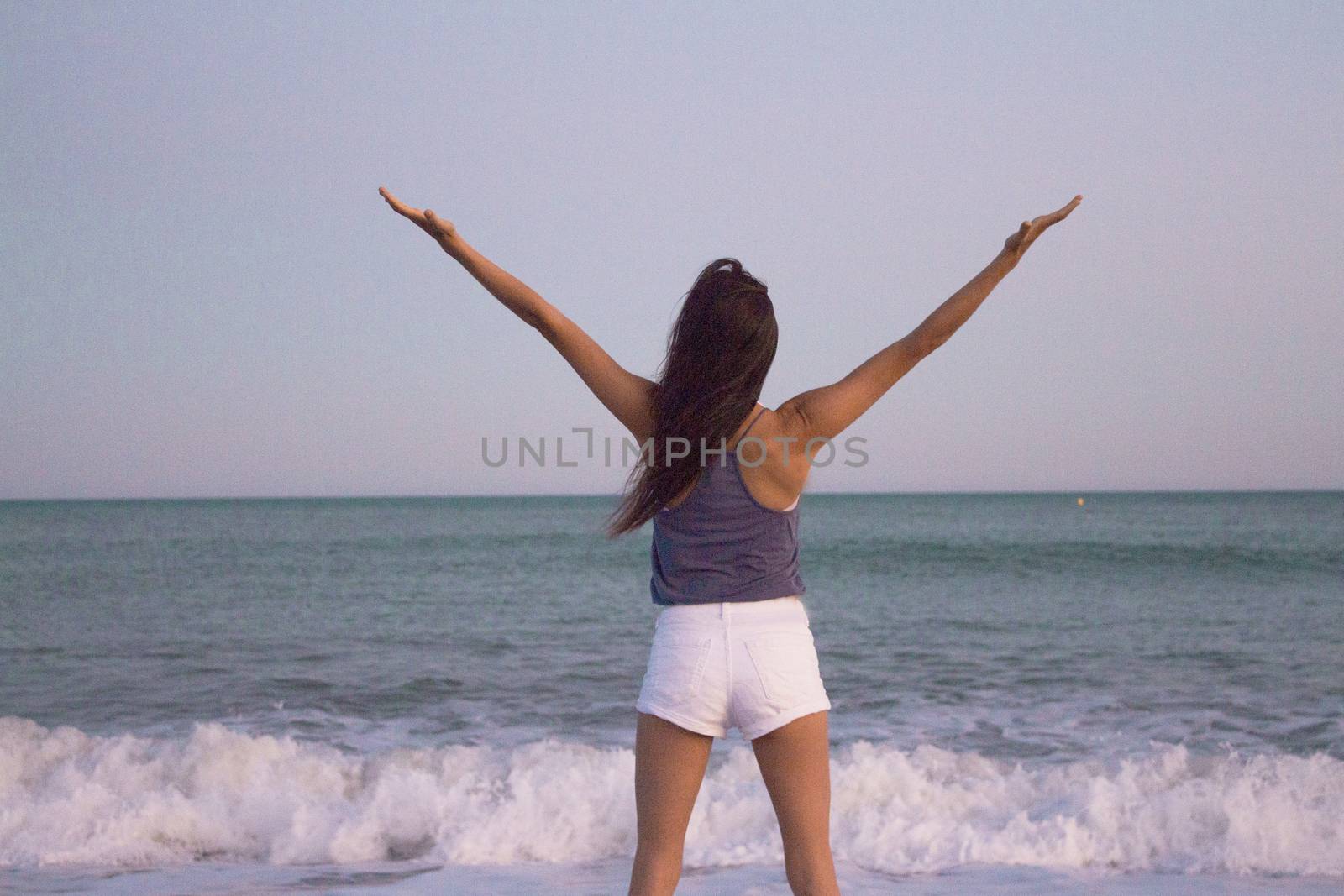 Mujer joven en la playa en actitud muy positiva y feliz. Precioso atardecer