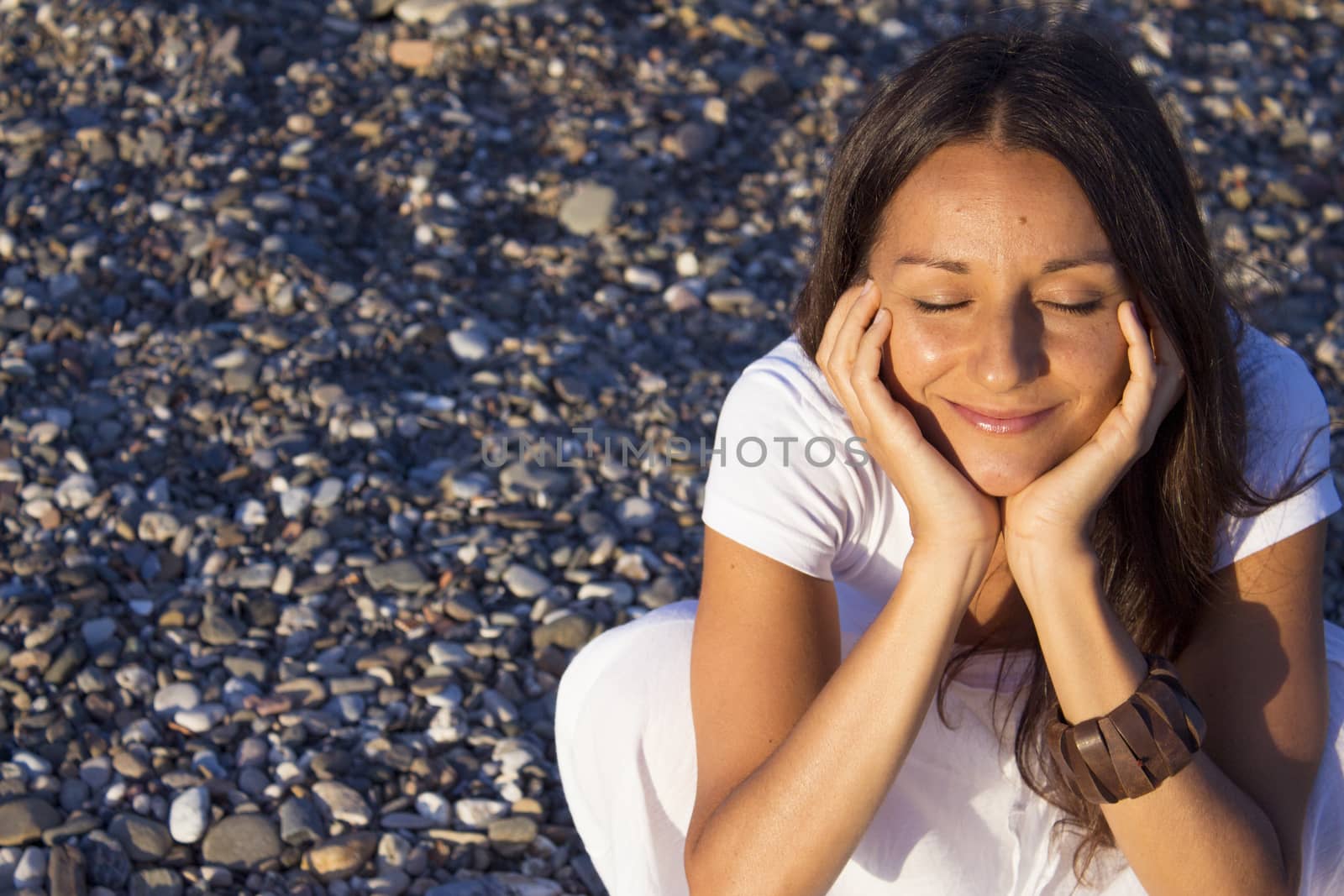 Woman sitting on stones with hands on the pensive face. Positive expression