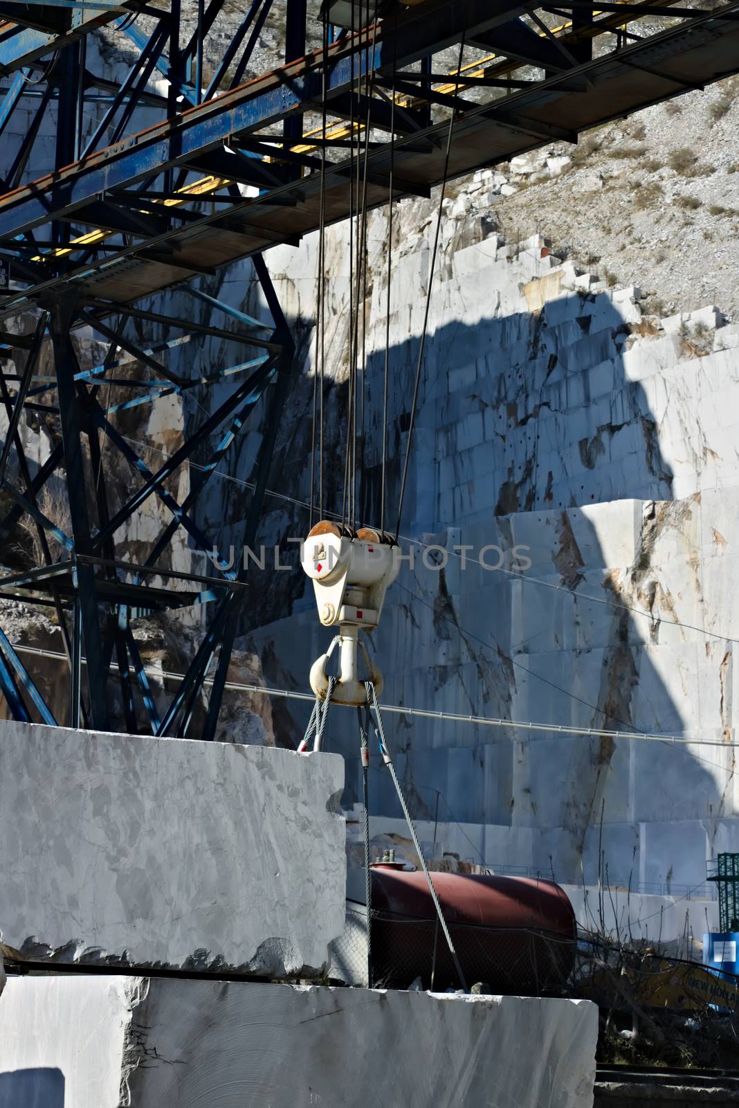 In a marble deposit on the Carrara mountains, an overhead crane is used to move the white marble blocks.