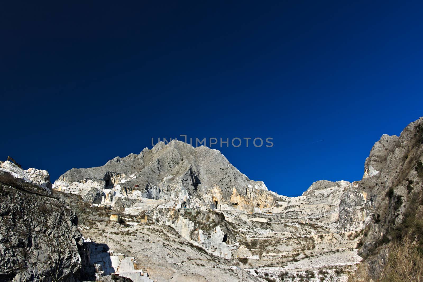 The precious white Carrara marble has been extracted from the Alpia Apuane quarries since Roman times. Today workers are helped by mechanical equipment (excavators, diamond wire machines and transport trucks).