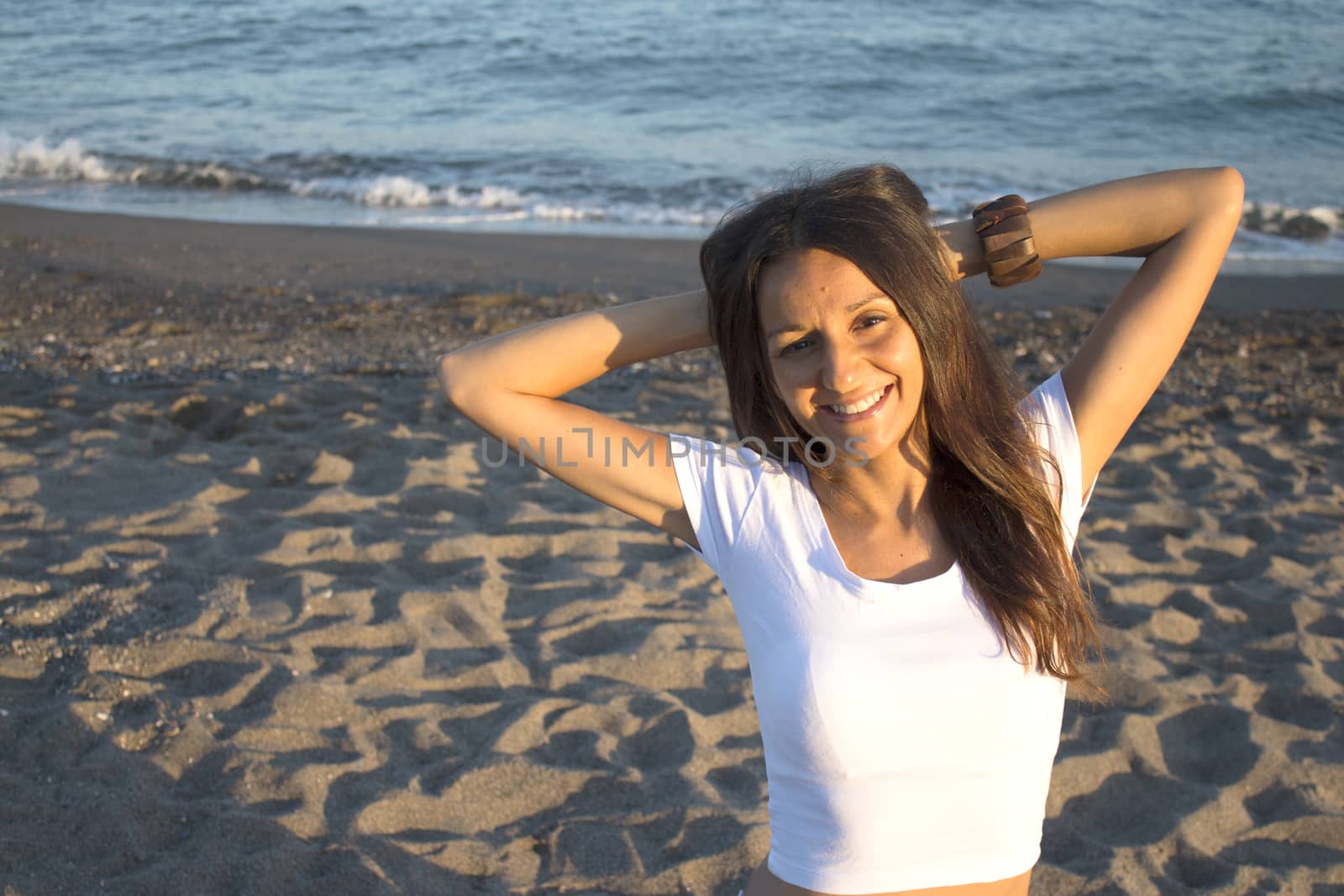 Girl with white t-shirt on the beach and her arms on the neck. Very happy