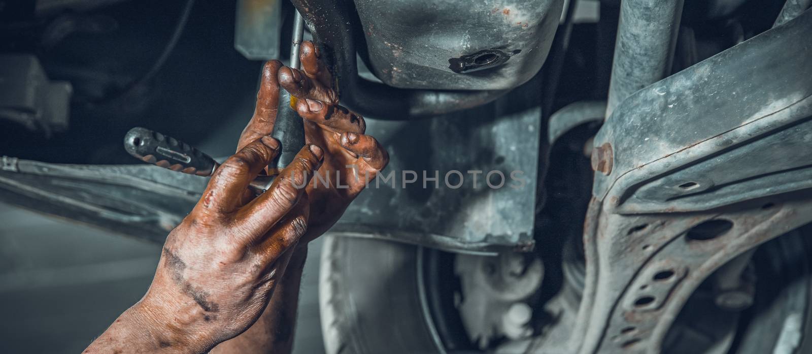 A car mechanic repairs a car at a car repair shop with a turnkey. close-up on hands.