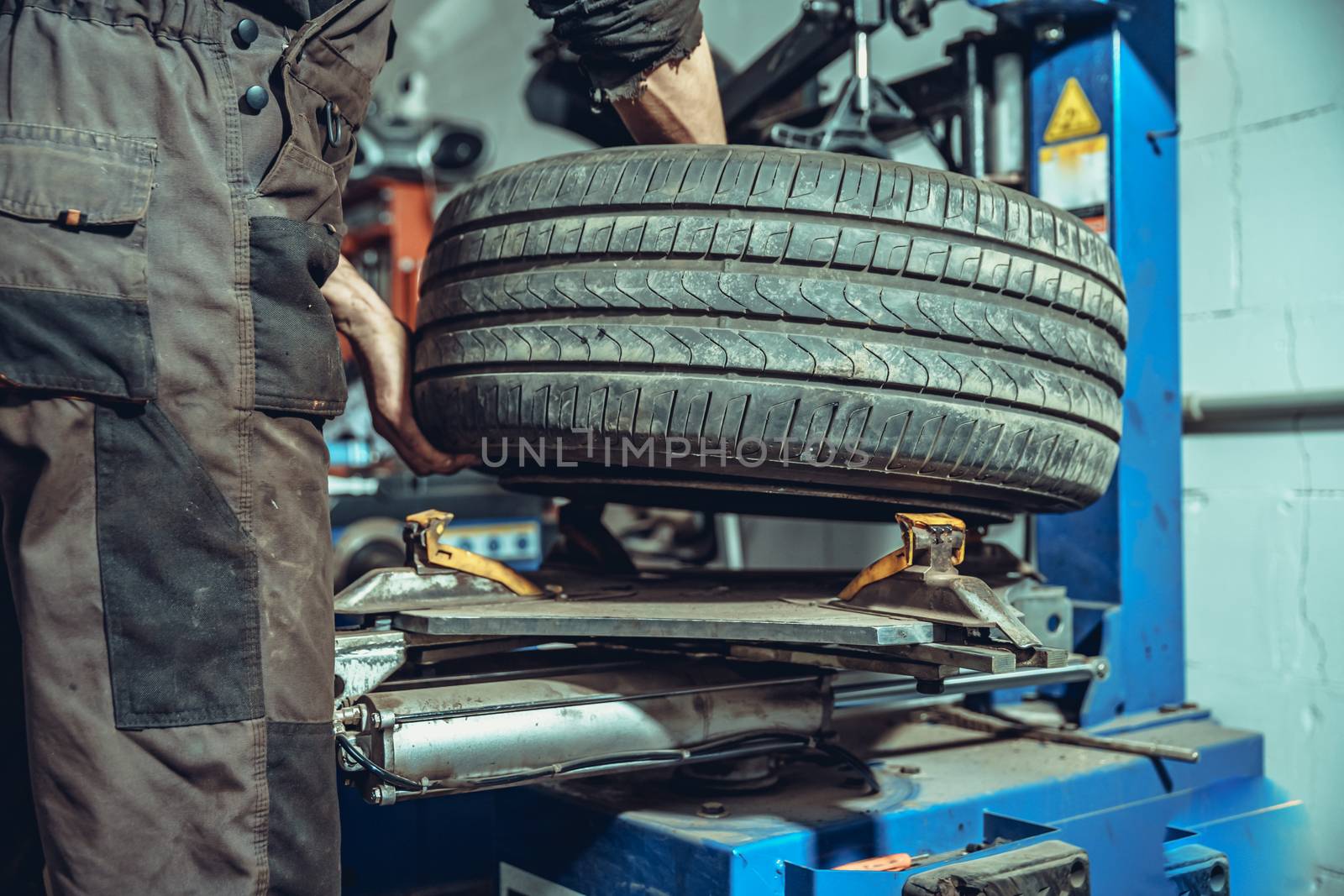 A technician changes tires on a car wheel on a special machine in a tire service.