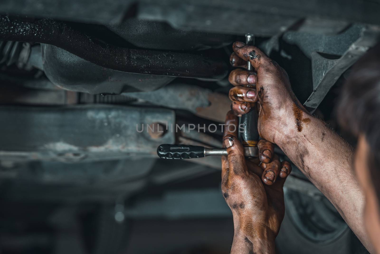 dirty hands of a technician while repairing a car.