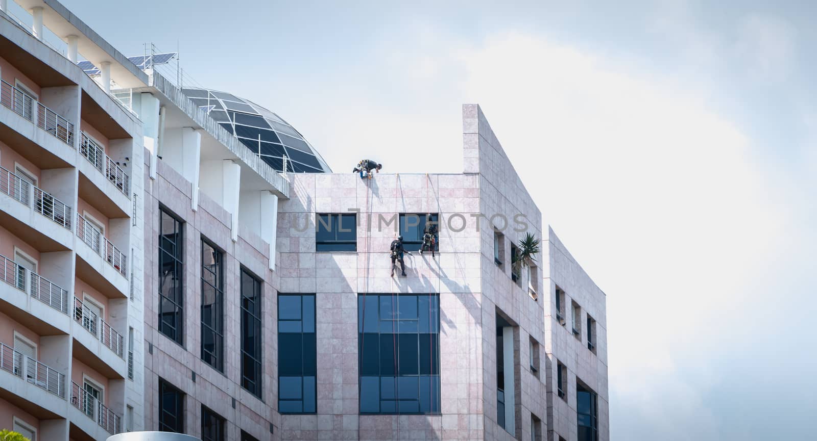 Lisbon, Portugal - May 7, 2018 - Man washing windows climbing a building in Expo district on a spring day
