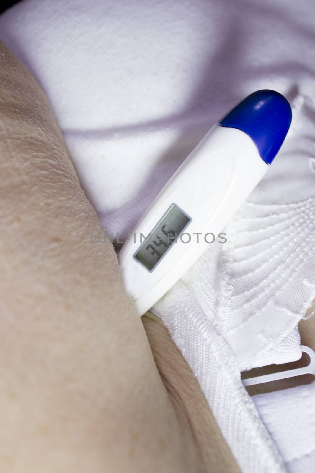 Digital thermometer measuring temperature to old woman in armpit