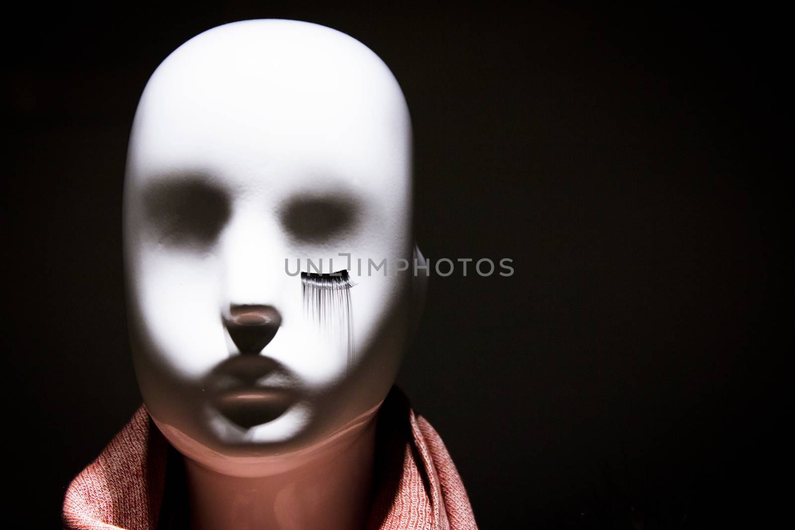 Female white mannequin head are eyelashes only in one eye. No people