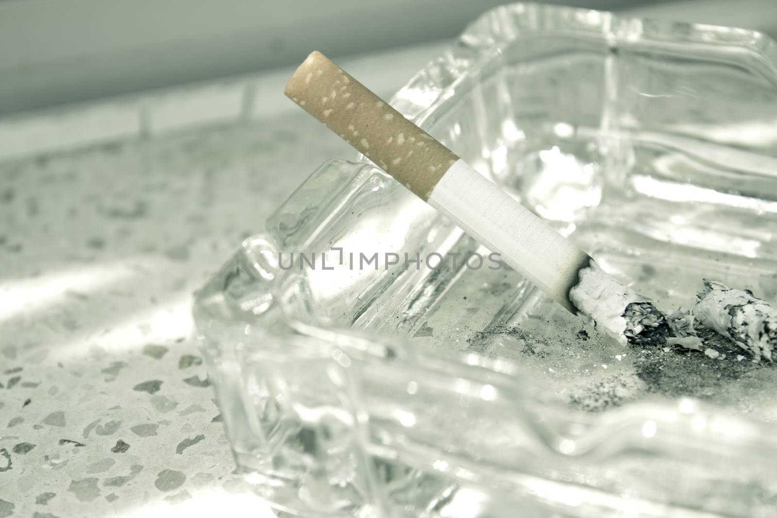 Lighted cigarette supported on ashtray. No people