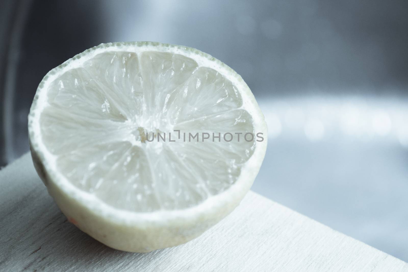 Half lemon cut on wooden cutting board. No people