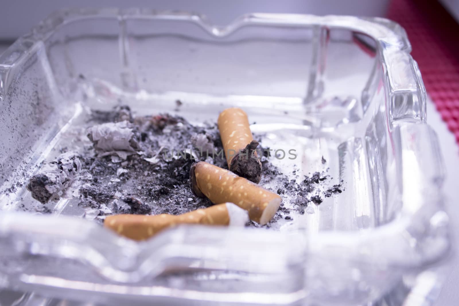 Ashtray with several cigarettes consumed and extinguished. Cigarette ash