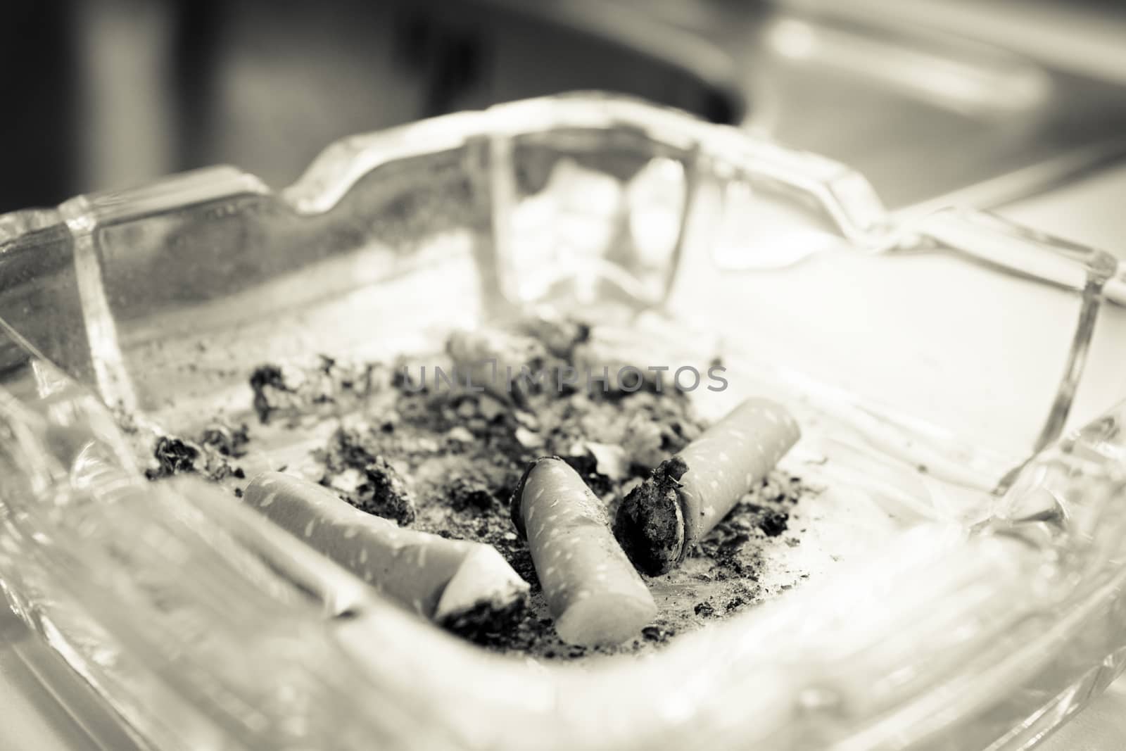 Ashtray with several cigarettes consumed and extinguished. Cigarette ash