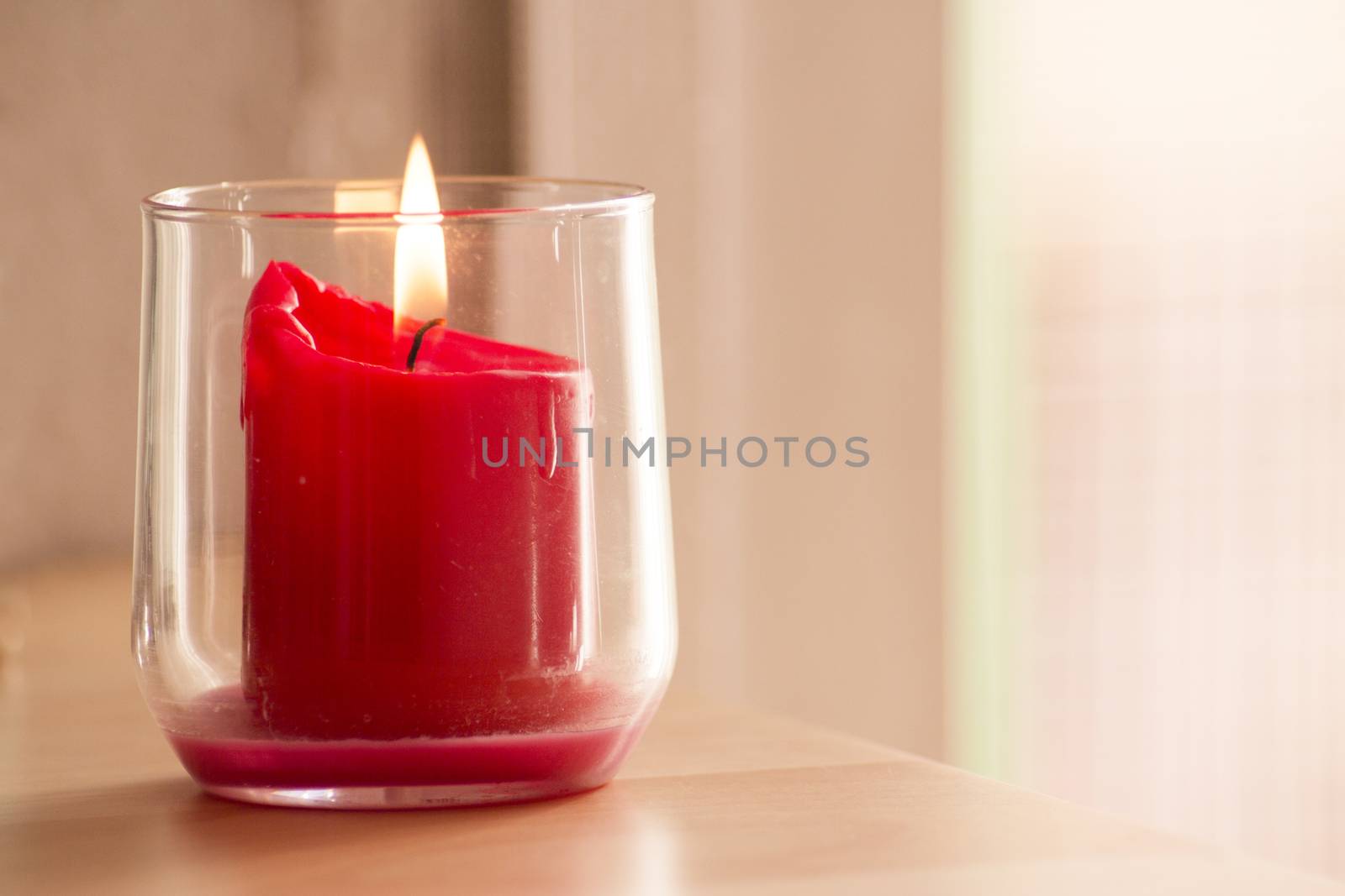 Burning red candle inside a clear glass vase. No people