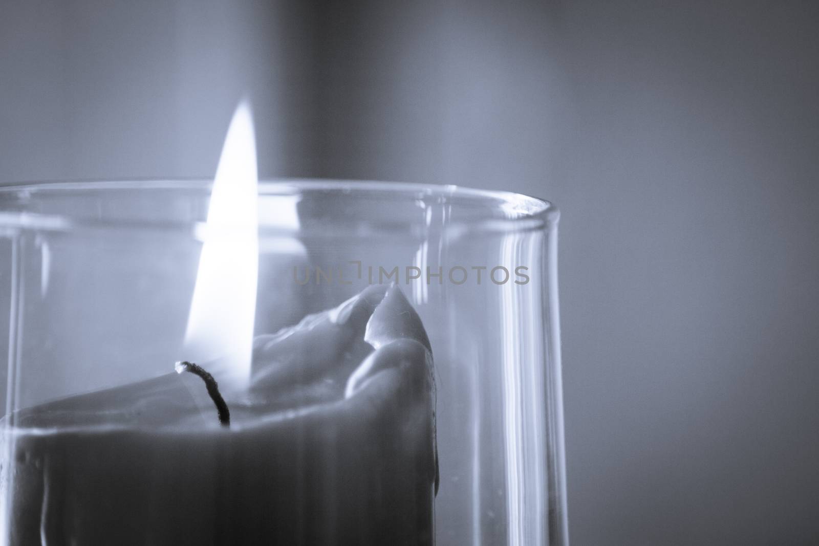 Burning red candle inside a clear glass vase. No people
