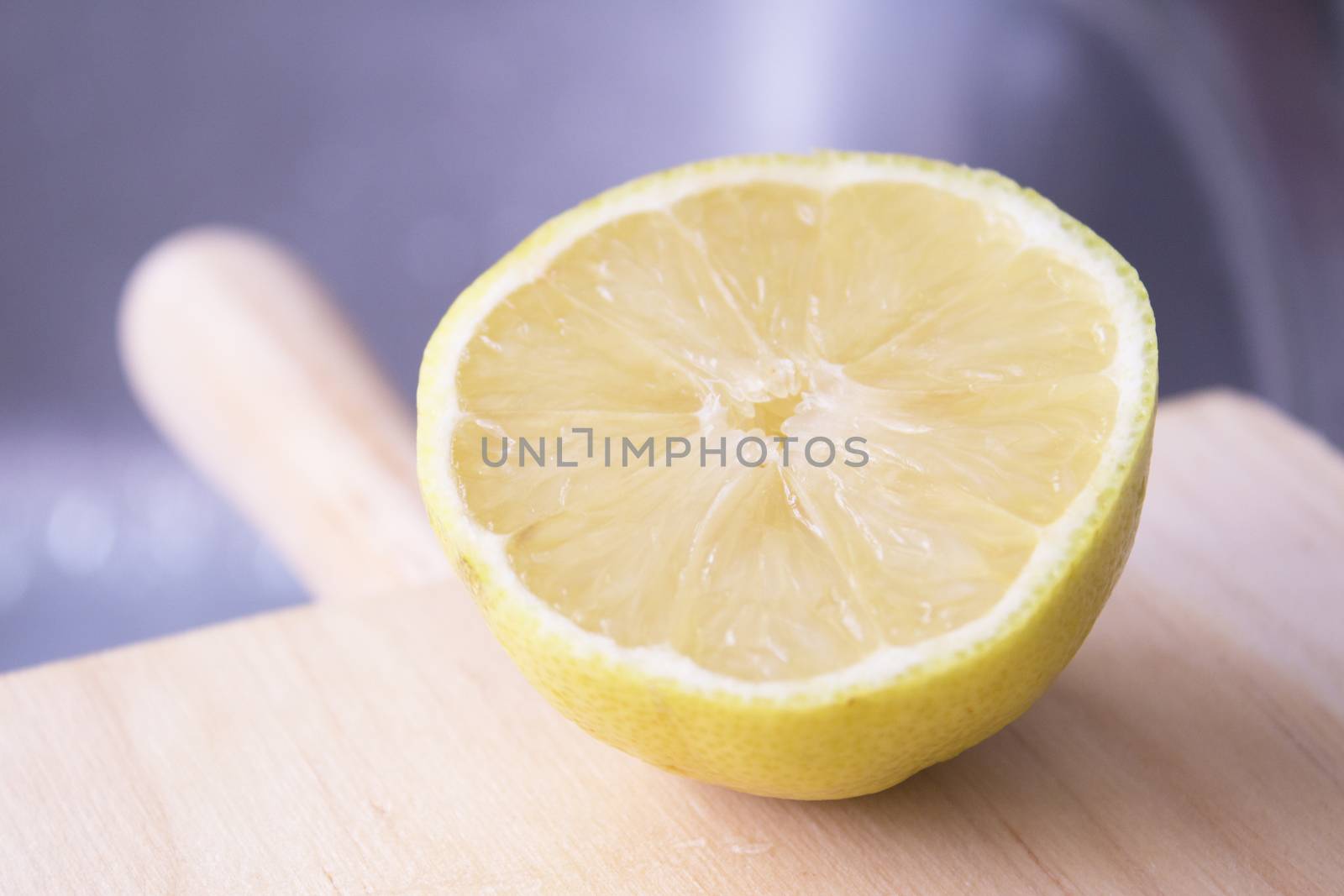 Half lemon cut on wooden cutting board. No people