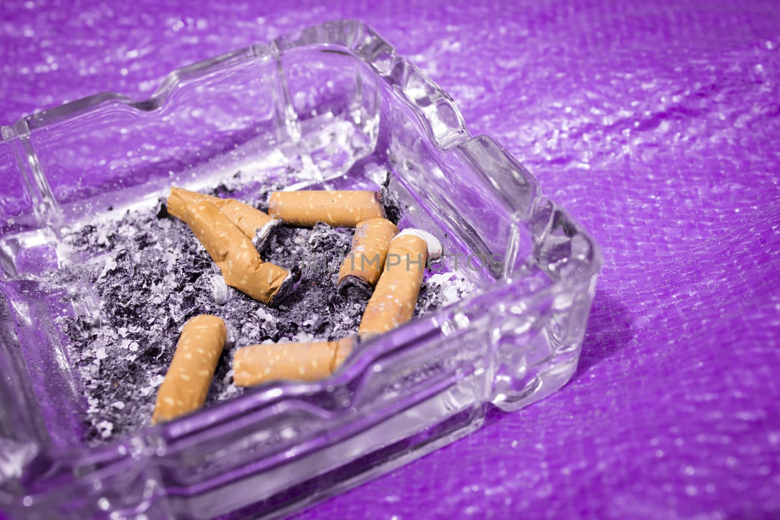 Ashtray with several cigarettes consumed and extinguished. Cigarette ash