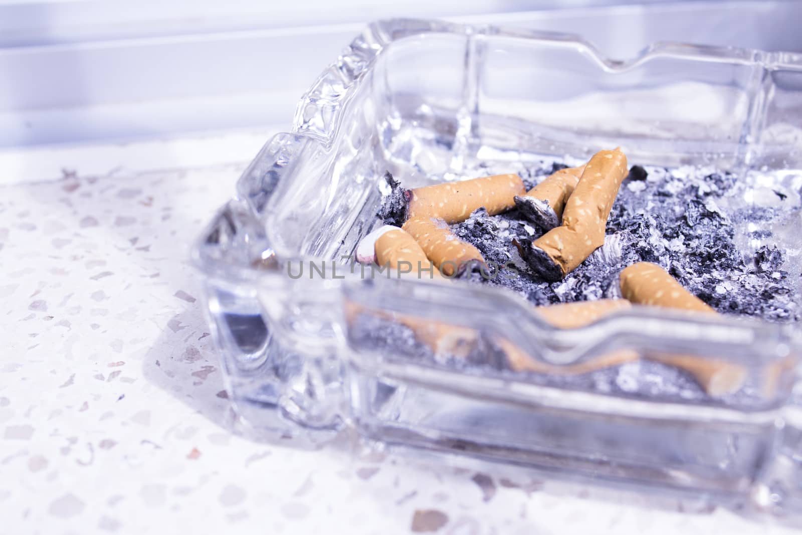 Ashtray with several cigarettes consumed and extinguished. Cigarette ash