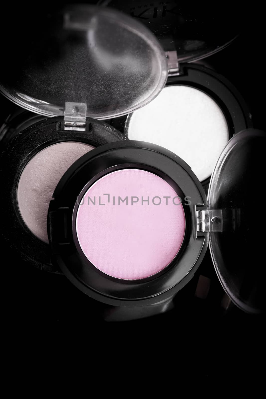 Various makeup shadows on dark background. No people