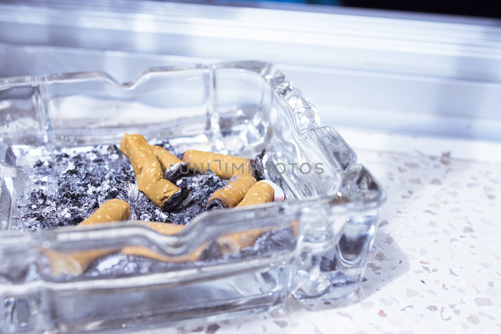 Ashtray with several cigarettes consumed and extinguished. Cigarette ash