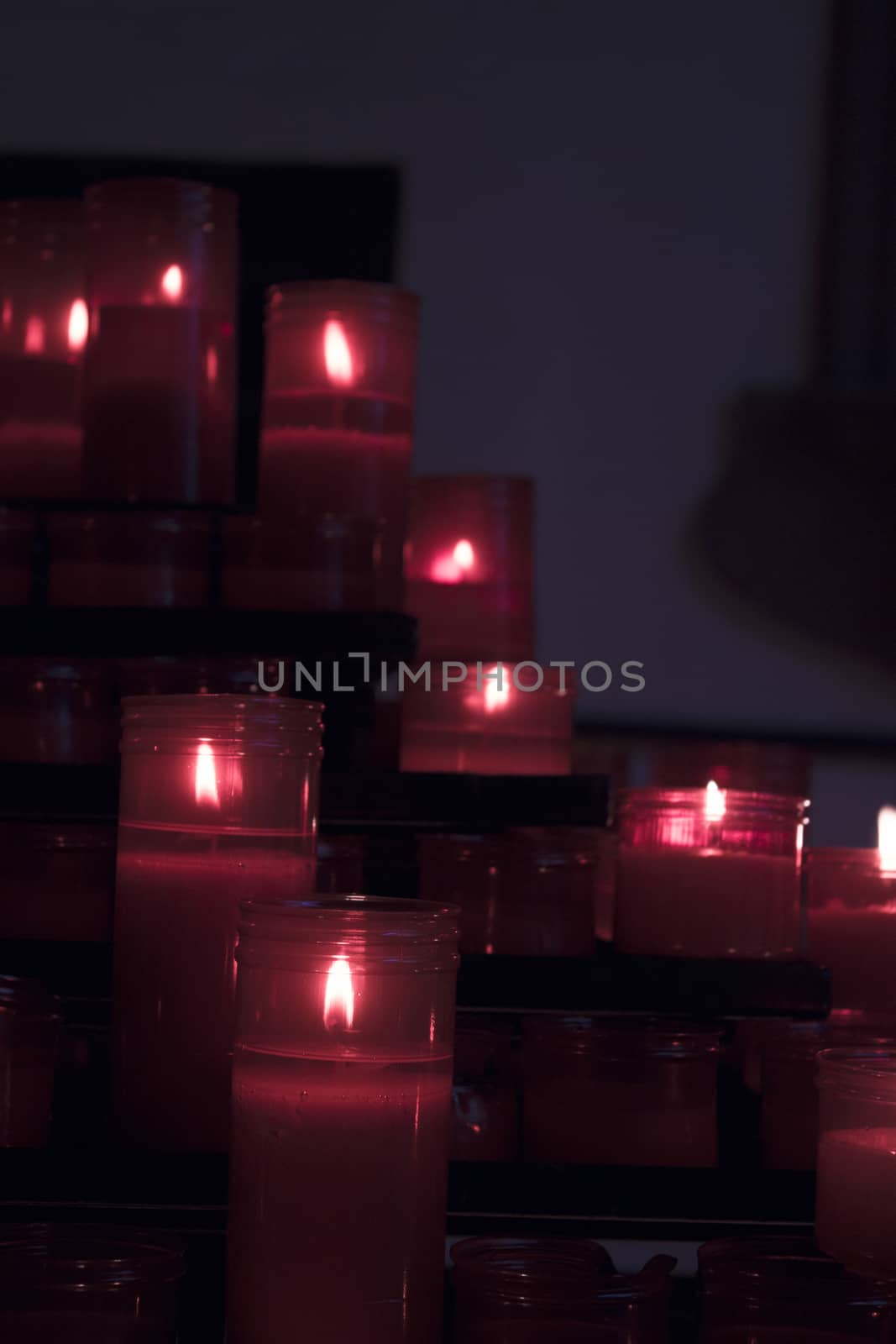 Many burning candles with red plastic sheath. No people