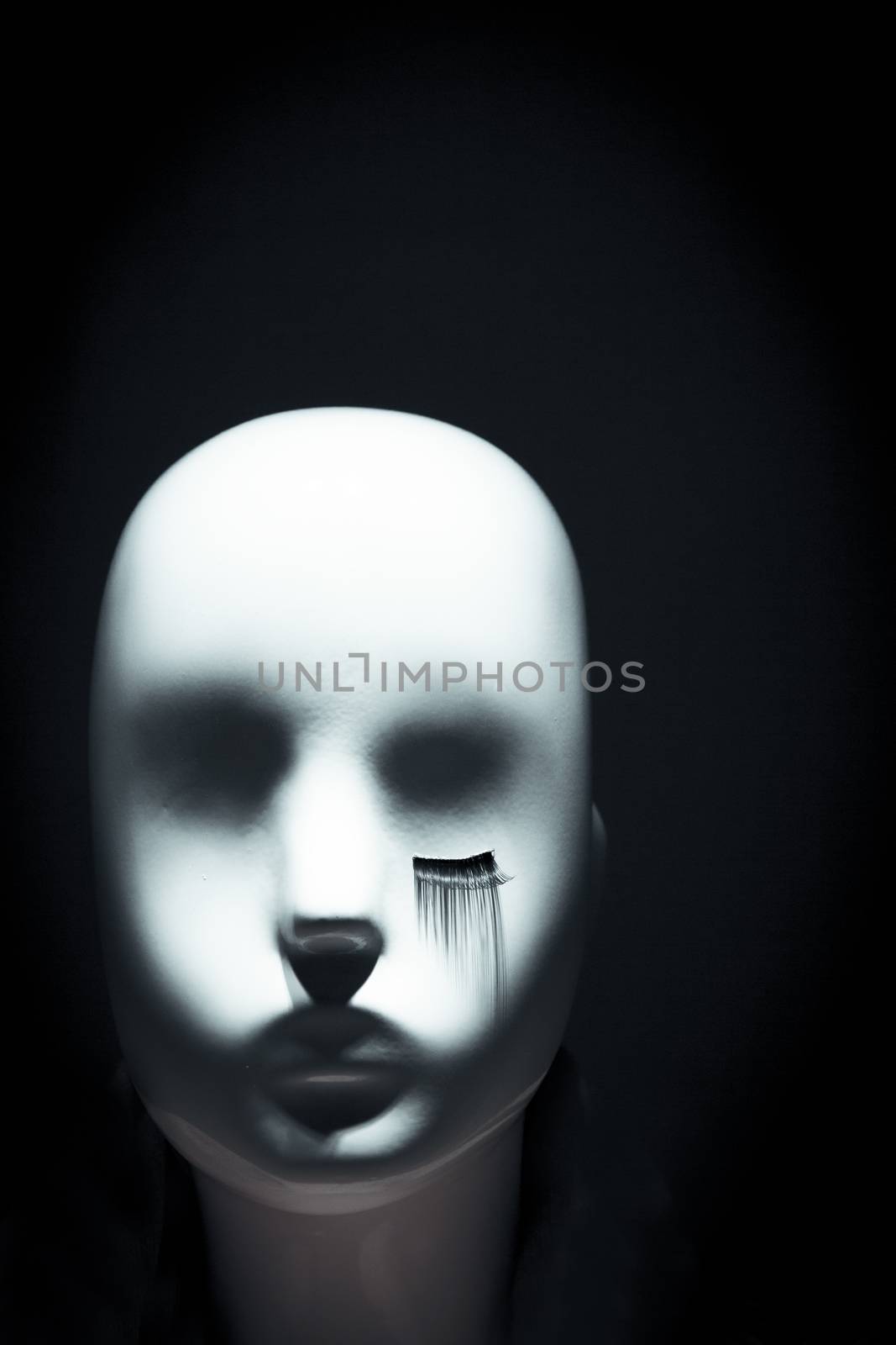 Female white mannequin head are eyelashes only in one eye. No people