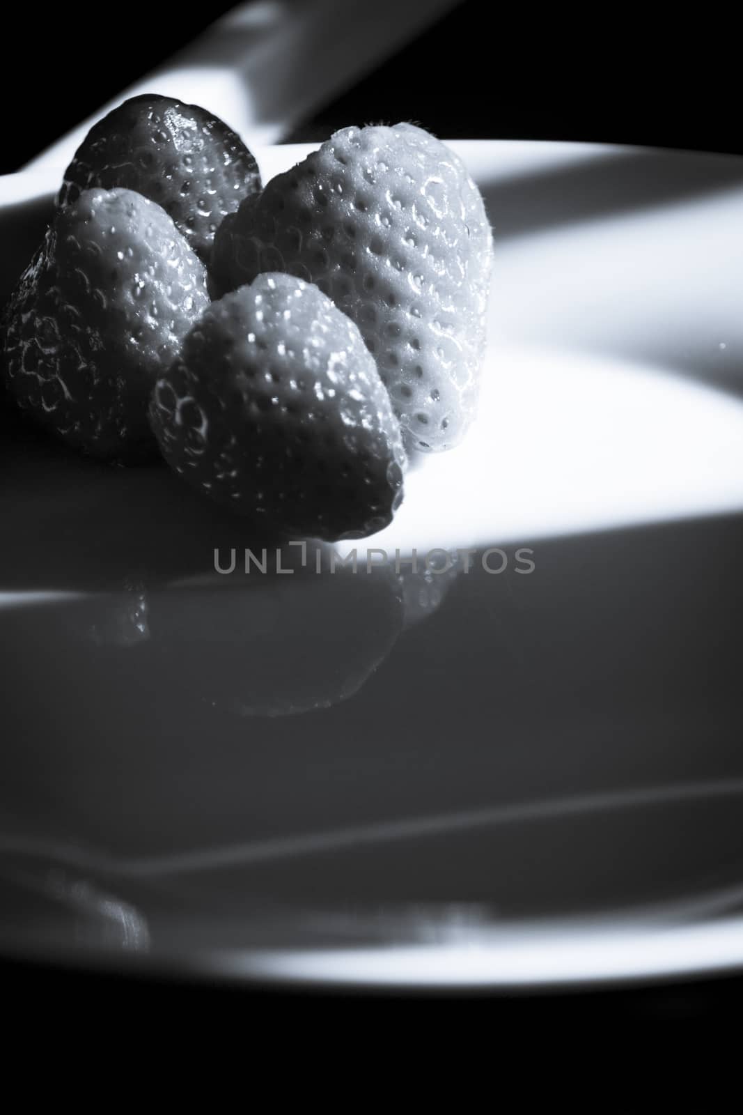 Ripe strawberries on a white plate and dark background. No people