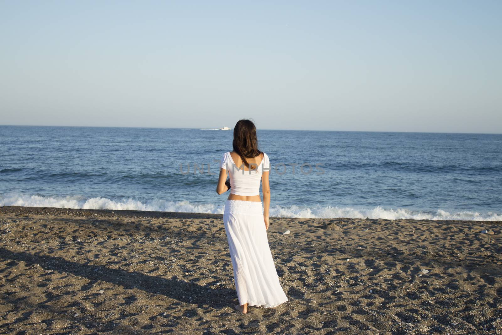 Girl dressed in white with her back to the beach. Tranquil scene