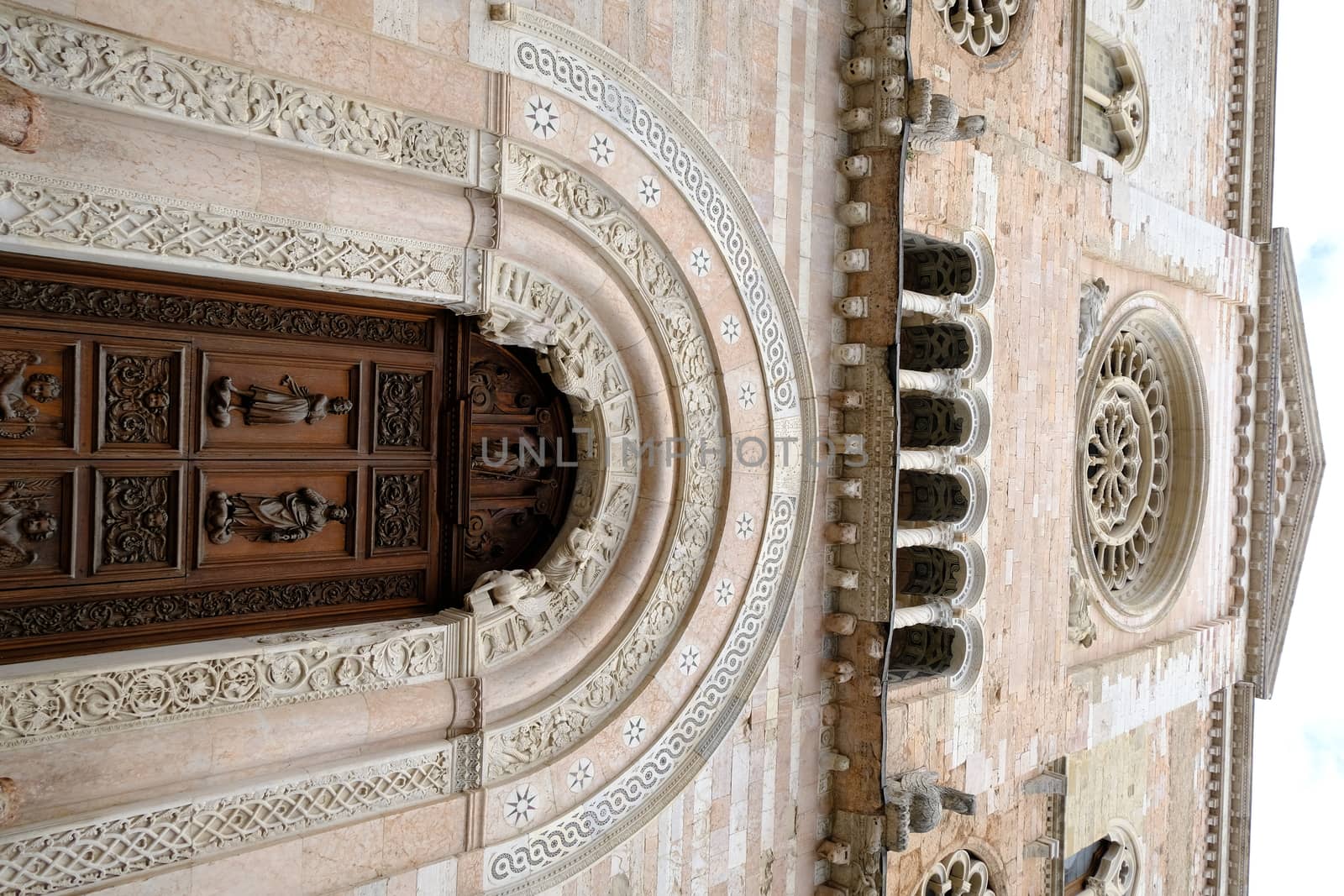 Foligno, Umbria, Italy. About october 2019.  Wooden door portal and carved light marble rosette of the Cathedral of San Feliciano in Foligno.