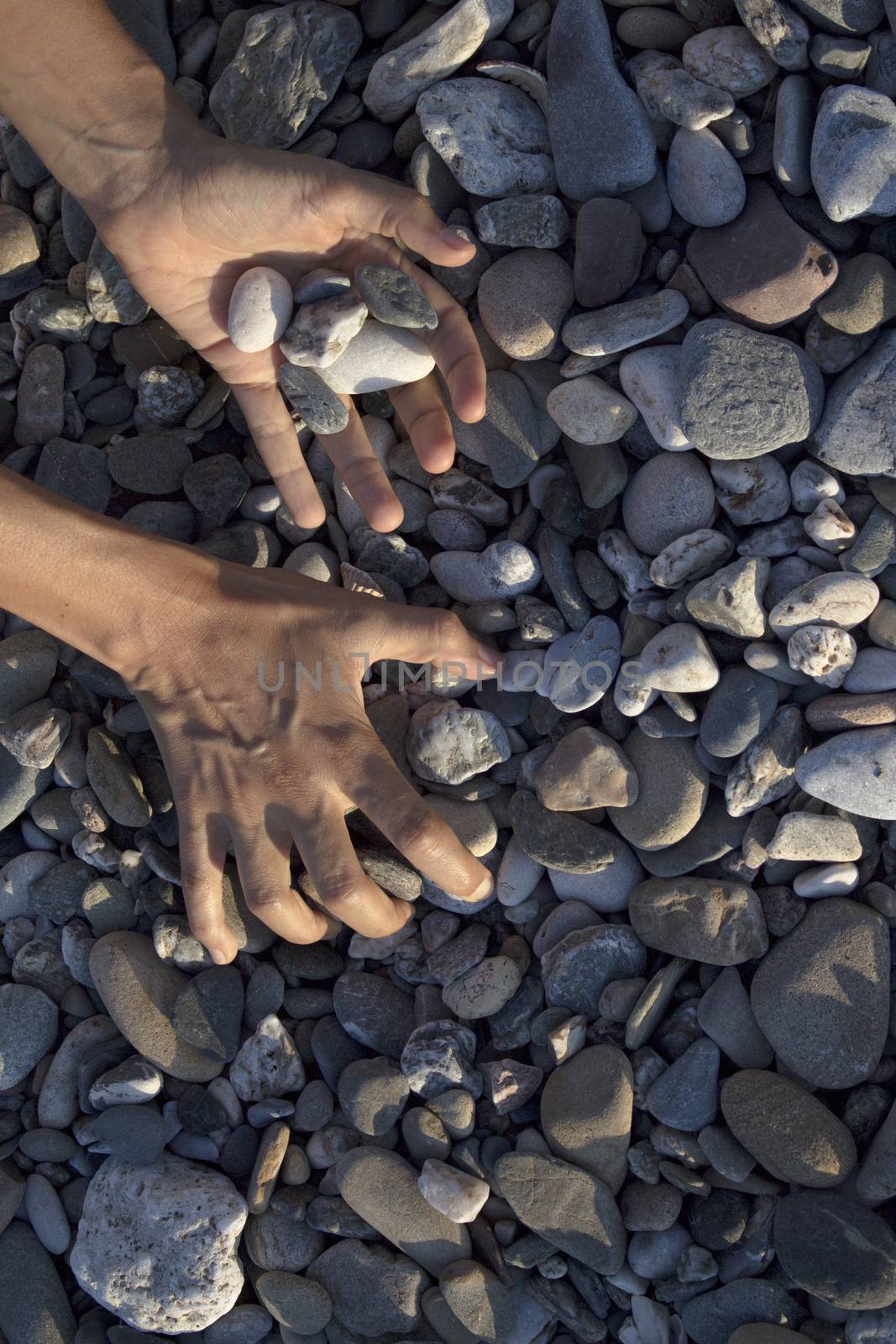 Woman hands touching stones on the beach. Grey stones