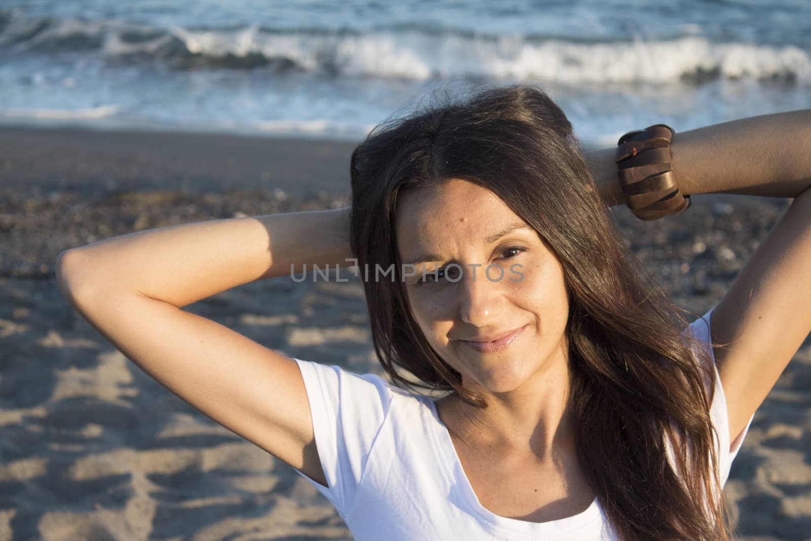 Girl with white t-shirt on the beach and her arms on the neck. Very happy