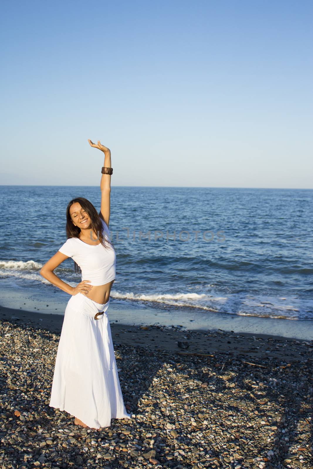 Attractive woman in white dress on the beach. Positive expression