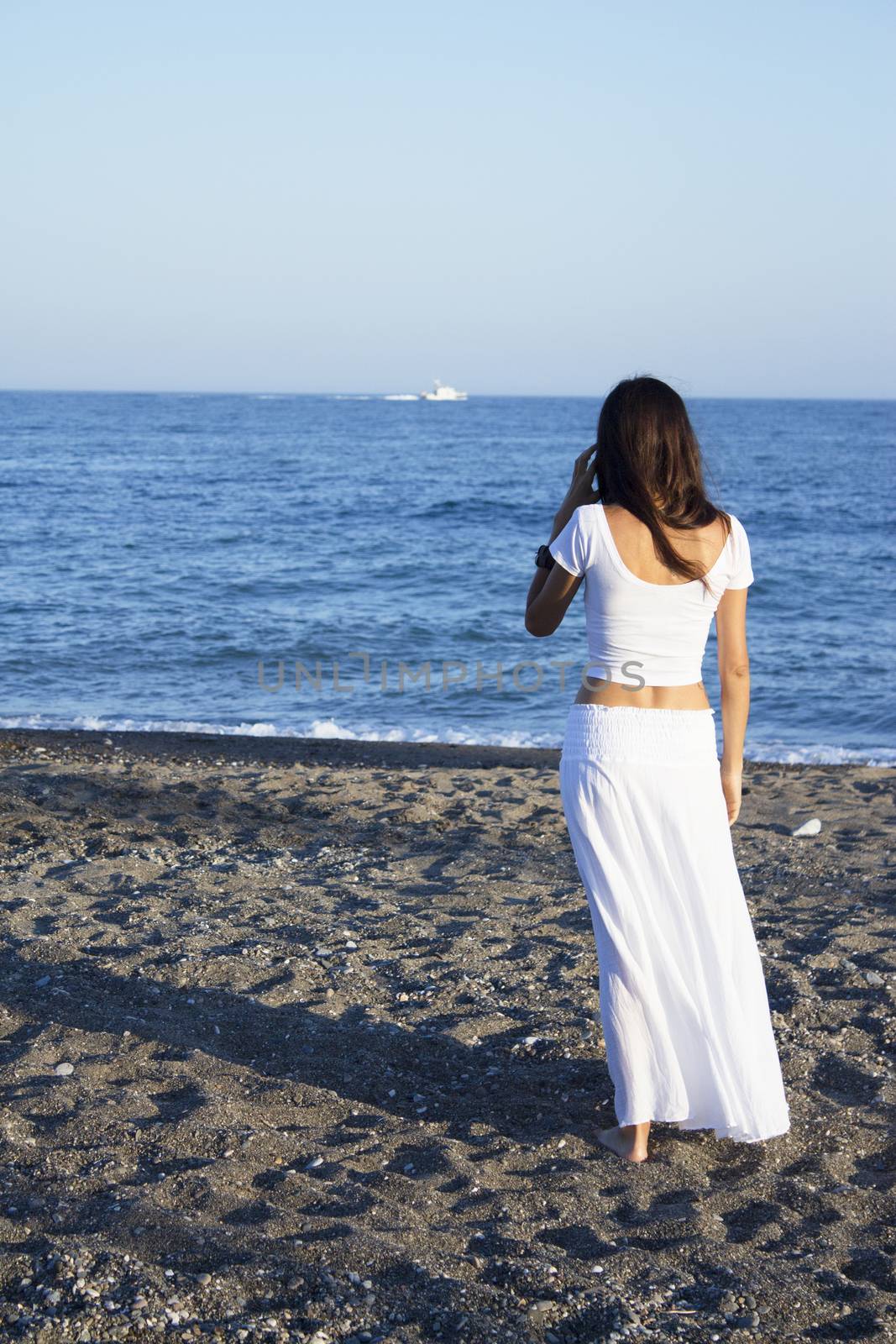 Girl dressed in white with her back to the beach. Tranquil scene