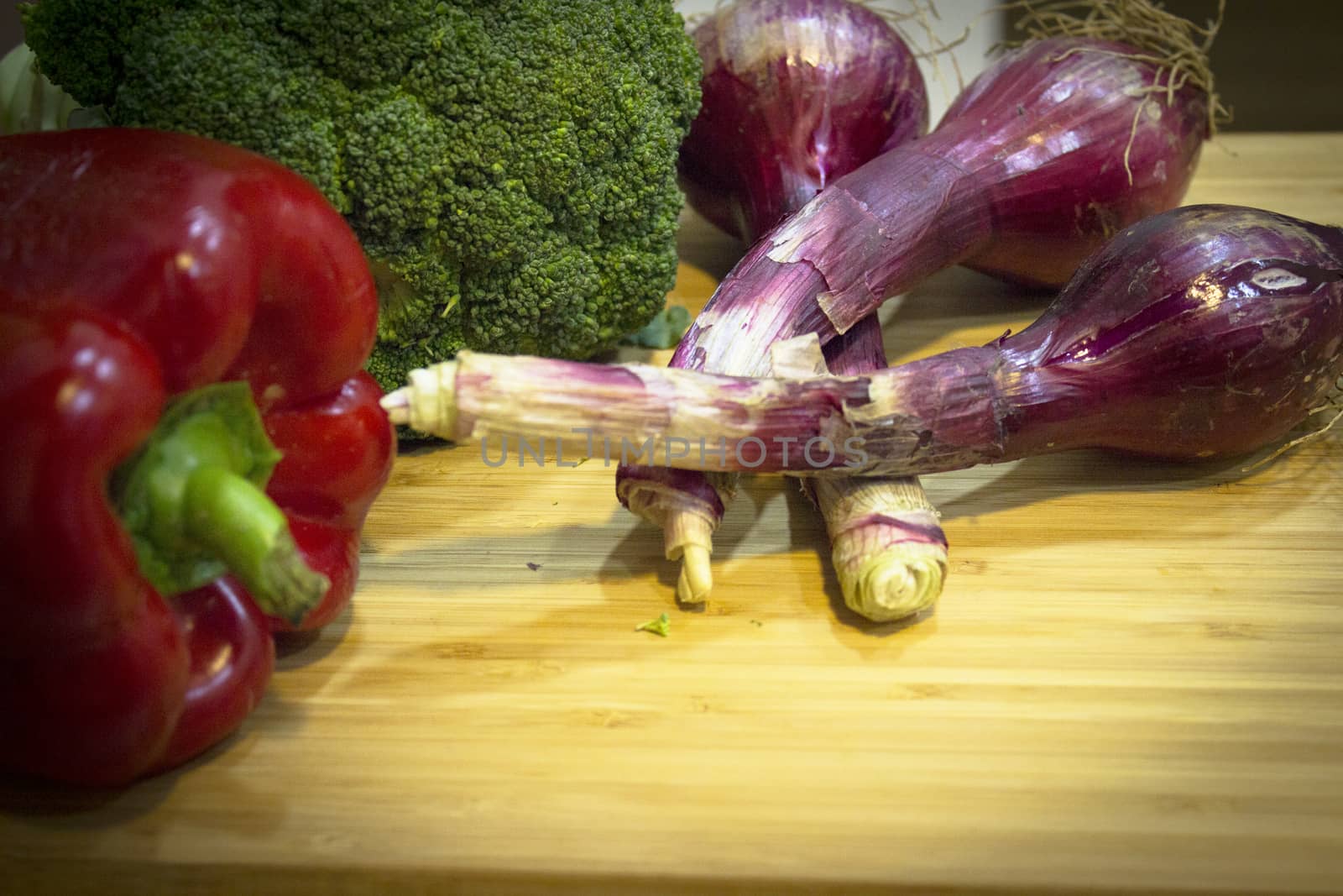 Fresh vegetables on a wooden cutting board. Broccoli, chives and bell pepper. No people
