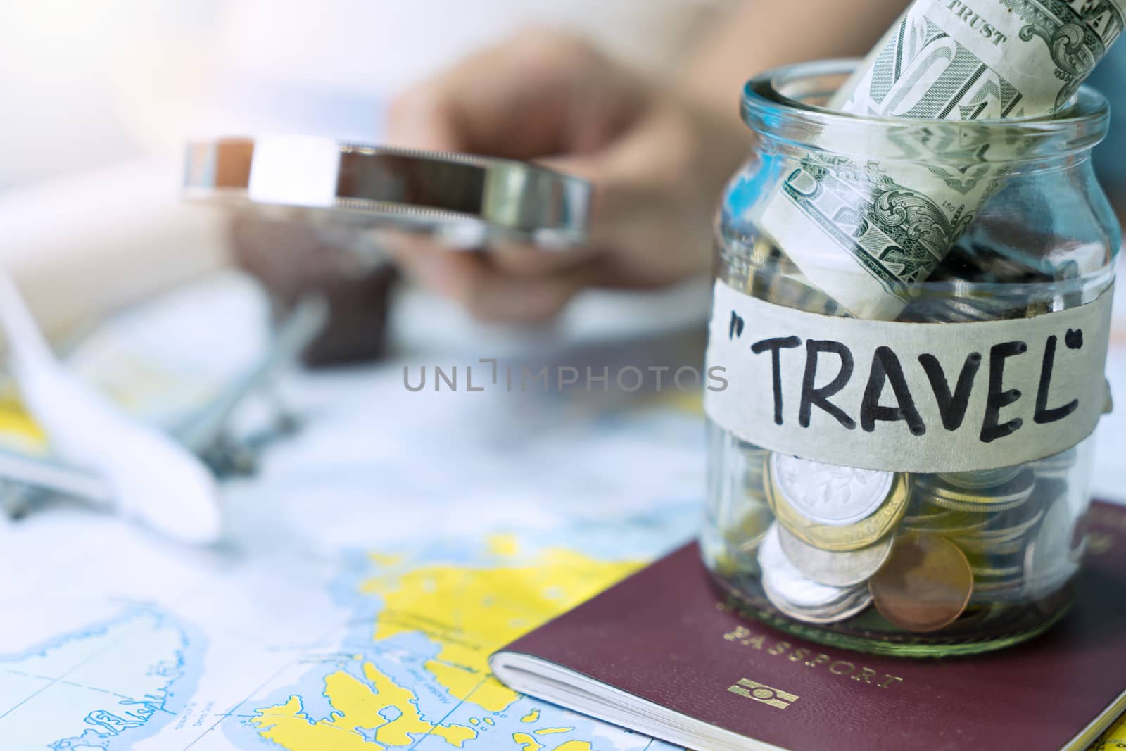 Saving money in a glass jar for travel on map by Buttus_casso