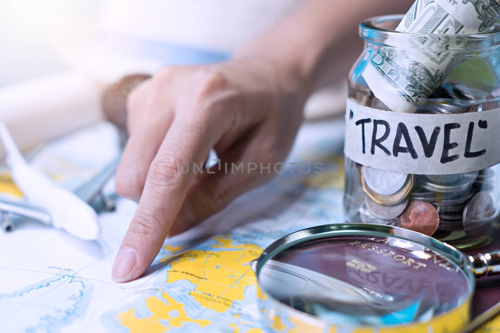 Saving money in a glass jar for travel on map