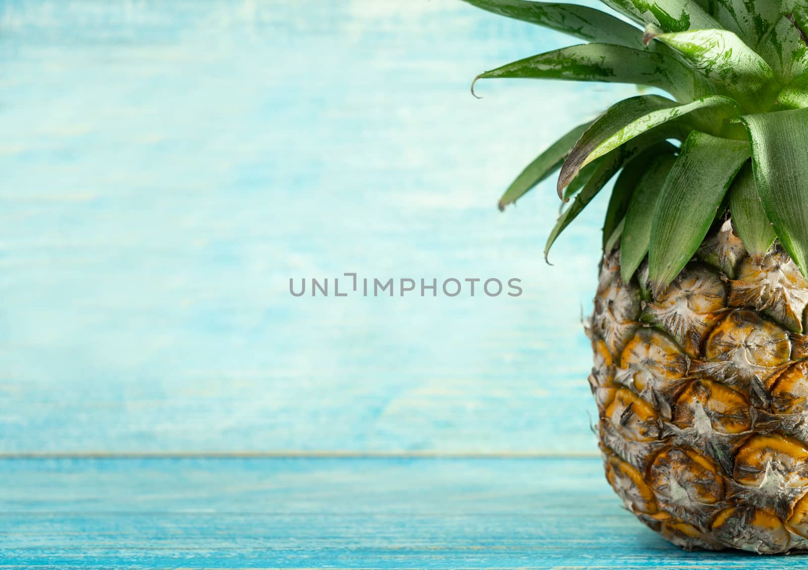 Pineapple with copy space on wooden background by Buttus_casso